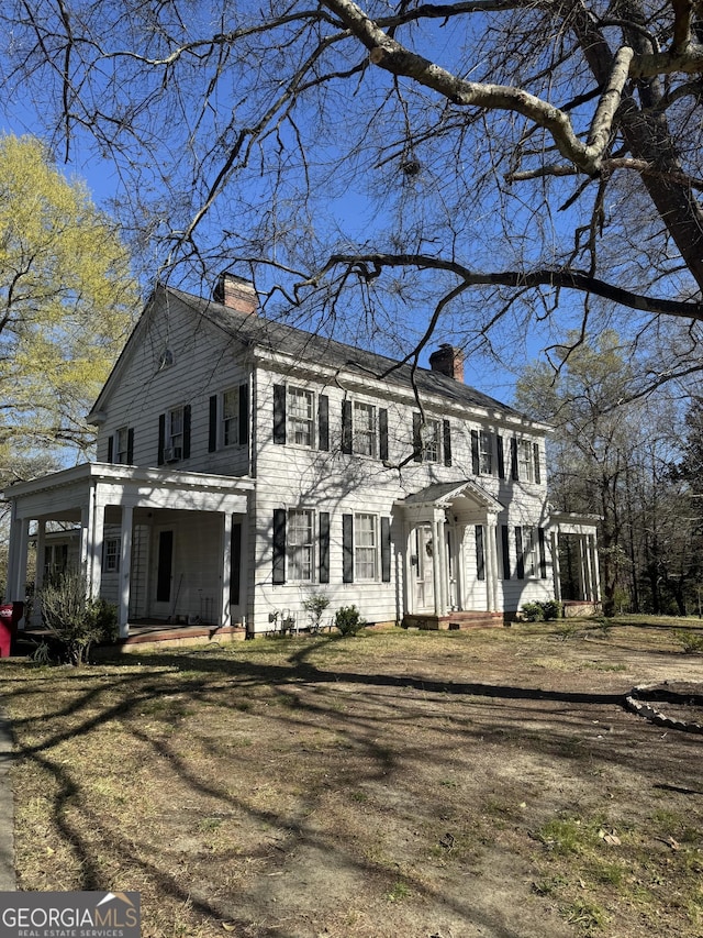colonial-style house featuring a porch, a pergola, and a chimney