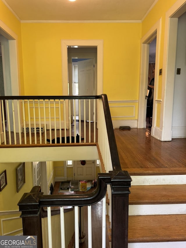 stairs featuring ornamental molding, wood finished floors, and a decorative wall