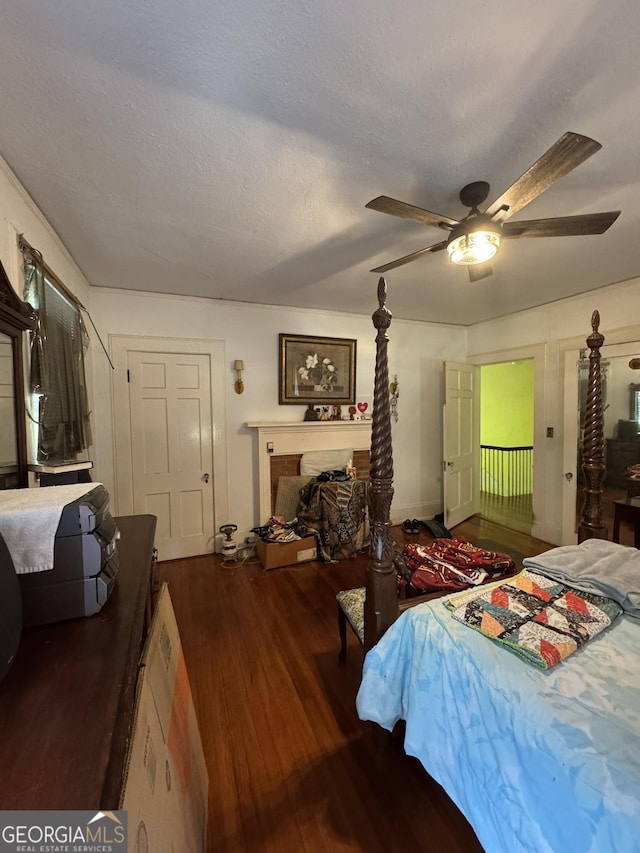 bedroom with a textured ceiling, a fireplace, a ceiling fan, and wood finished floors