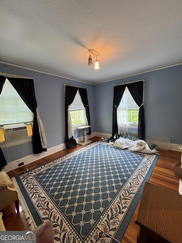 bedroom featuring multiple windows, ornamental molding, and wood finished floors