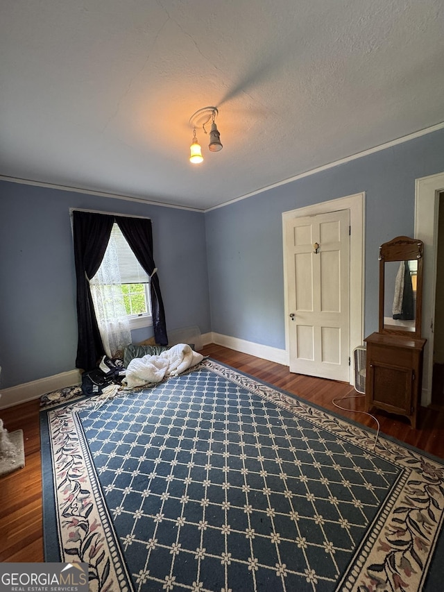 bedroom featuring baseboards, crown molding, and wood finished floors