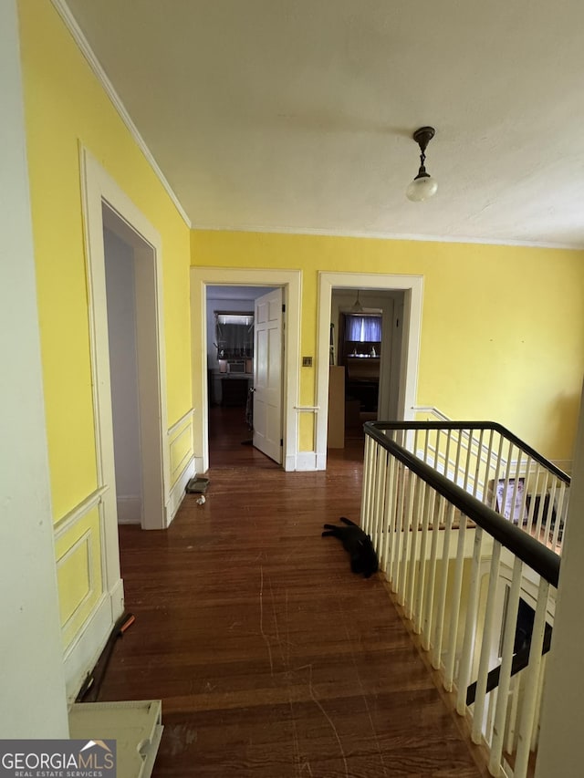 hallway with crown molding, wood finished floors, and an upstairs landing