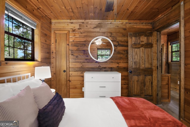 bedroom with multiple windows, wood ceiling, and wooden walls