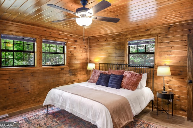 bedroom featuring hardwood / wood-style flooring, wood ceiling, wooden walls, and multiple windows