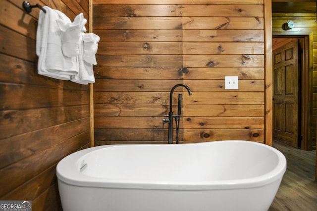 bathroom featuring a tub to relax in and wooden walls