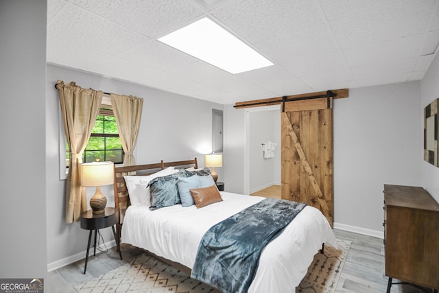 bedroom with a barn door and light hardwood / wood-style floors