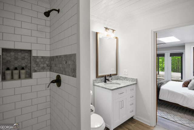 bathroom featuring vanity, hardwood / wood-style floors, crown molding, and a tile shower