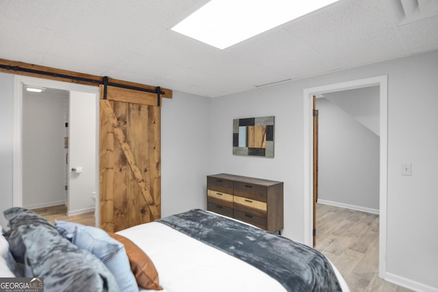 bedroom with a barn door and light wood-type flooring