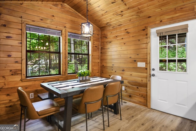 dining area featuring wood ceiling, lofted ceiling, wooden walls, and light hardwood / wood-style floors