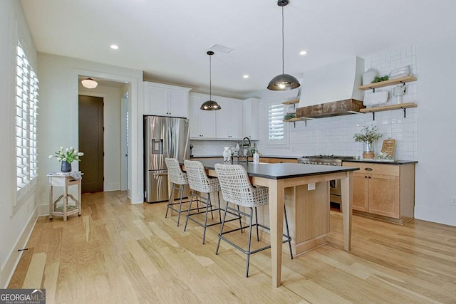 kitchen with decorative light fixtures, appliances with stainless steel finishes, a kitchen island, custom range hood, and white cabinets