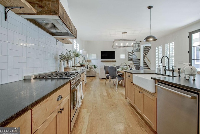 kitchen with pendant lighting, sink, appliances with stainless steel finishes, backsplash, and light hardwood / wood-style floors