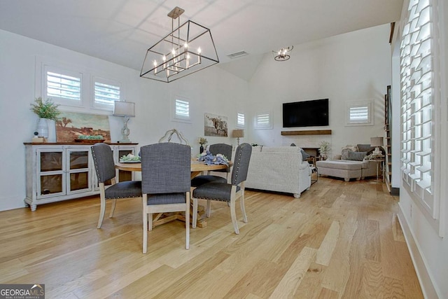 dining space featuring an inviting chandelier, high vaulted ceiling, and light wood-type flooring