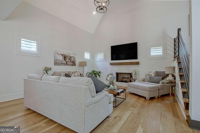 living room featuring a wealth of natural light, a brick fireplace, high vaulted ceiling, and light wood-type flooring