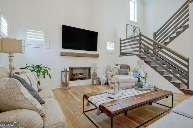 living room featuring wood-type flooring, a towering ceiling, and a fireplace