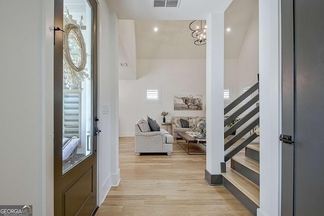 entryway featuring an inviting chandelier, a high ceiling, and light wood-type flooring