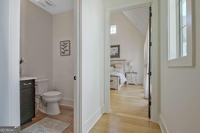 bathroom featuring hardwood / wood-style flooring, vanity, vaulted ceiling, and toilet