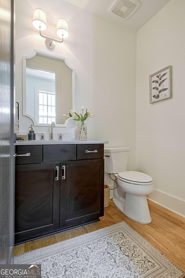 bathroom featuring vanity, hardwood / wood-style flooring, and toilet