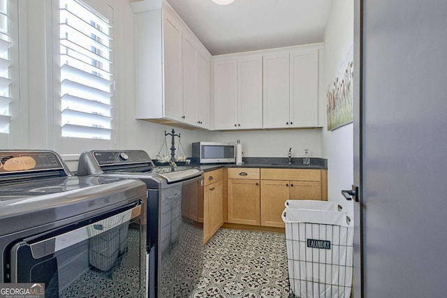 laundry room featuring sink, washer and clothes dryer, and cabinets