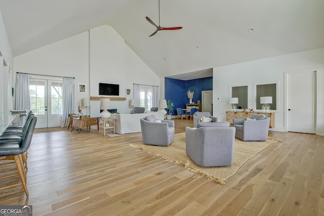 living room featuring ceiling fan, high vaulted ceiling, light wood-type flooring, and french doors