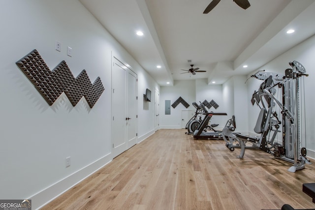 workout area with ceiling fan, electric panel, and light wood-type flooring