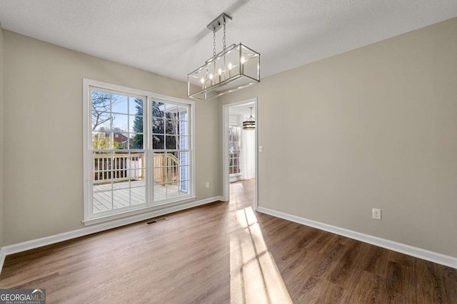 unfurnished dining area featuring hardwood / wood-style floors and a textured ceiling