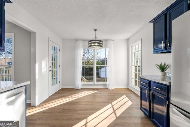 dining area with a textured ceiling, wood-type flooring, and a chandelier