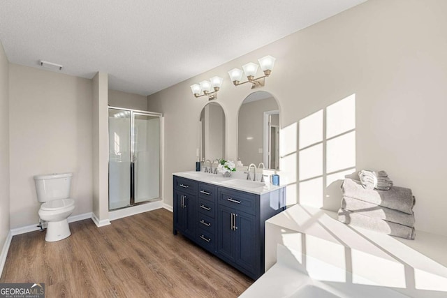 bathroom with walk in shower, toilet, a textured ceiling, vanity, and hardwood / wood-style flooring