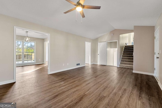 unfurnished living room featuring dark wood-type flooring, vaulted ceiling, and ceiling fan with notable chandelier