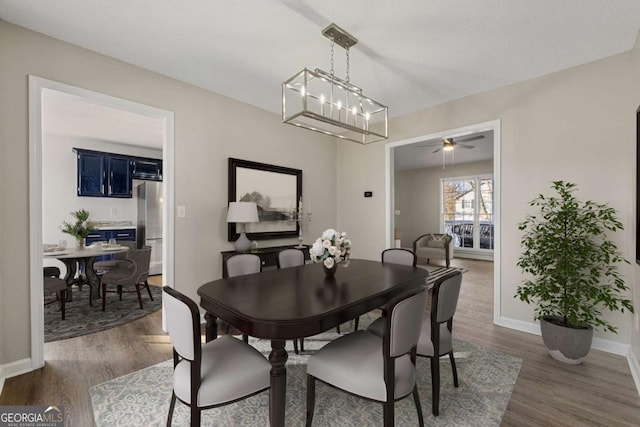 dining space featuring ceiling fan with notable chandelier and dark hardwood / wood-style flooring