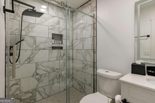 bathroom featuring a shower with door, vanity, and toilet