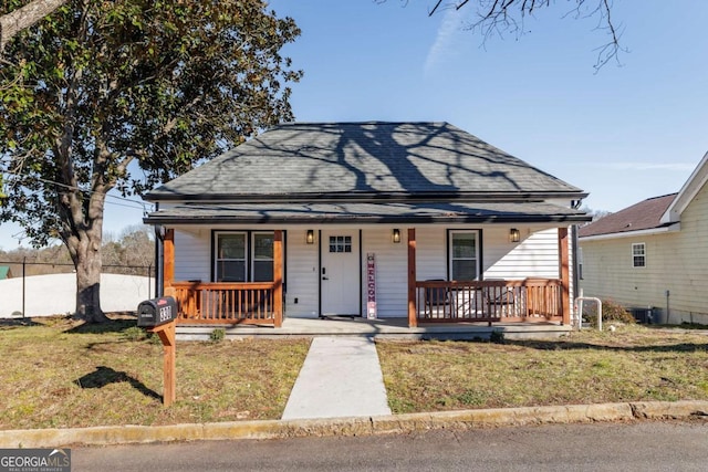 bungalow-style house featuring a front yard, central air condition unit, and a porch