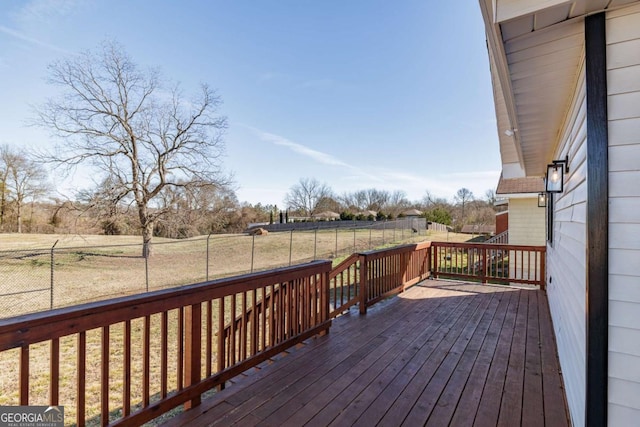 wooden deck with a rural view and a lawn