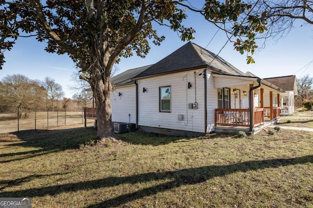 view of property exterior with central AC, covered porch, and a lawn