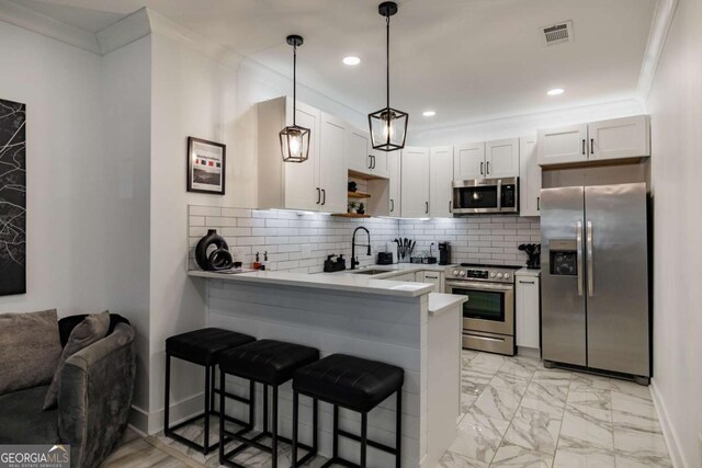 kitchen featuring hanging light fixtures, a kitchen breakfast bar, kitchen peninsula, stainless steel appliances, and white cabinets