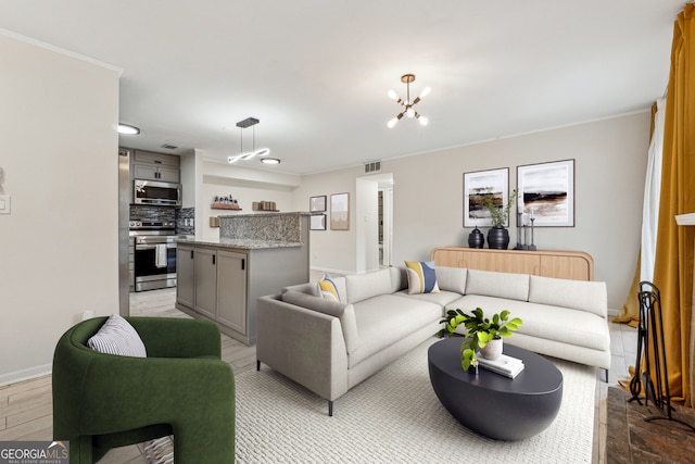 living area with visible vents, baseboards, ornamental molding, light wood-style flooring, and an inviting chandelier