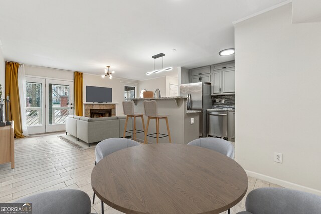 kitchen featuring gray cabinets, a tile fireplace, stainless steel fridge, backsplash, and light stone countertops