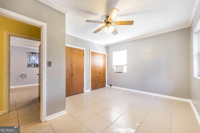 unfurnished bedroom with multiple closets, crown molding, light tile patterned flooring, and ceiling fan