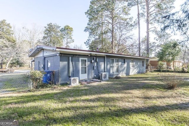 rear view of property with ac unit and a lawn