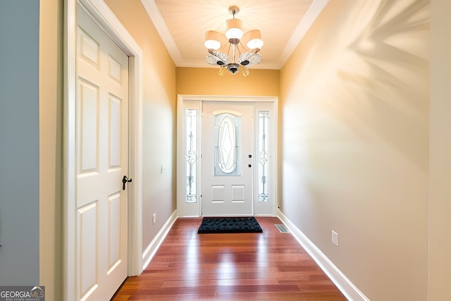 foyer featuring a notable chandelier, ornamental molding, and dark hardwood / wood-style floors