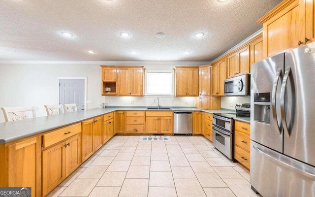 kitchen featuring sink, crown molding, a breakfast bar, stainless steel appliances, and kitchen peninsula