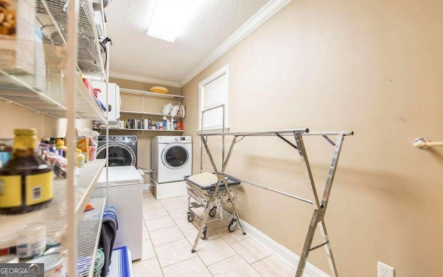 washroom featuring light tile patterned floors, crown molding, washer and clothes dryer, and a textured ceiling