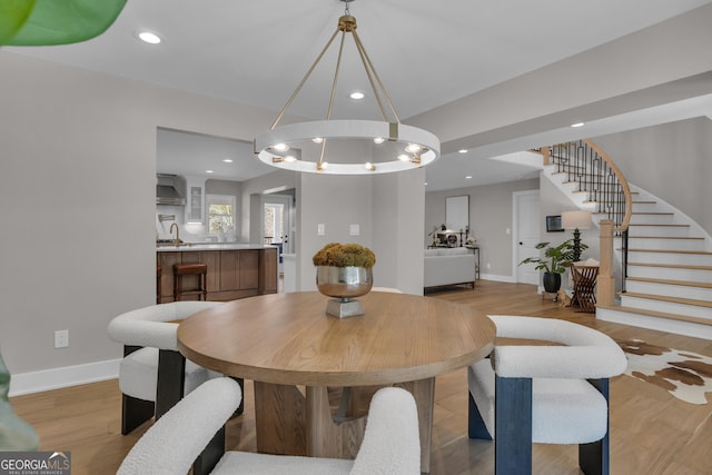 dining area featuring an inviting chandelier, sink, and light hardwood / wood-style flooring