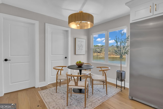 dining area featuring light wood-type flooring and a water view