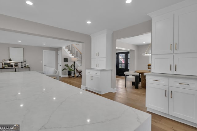 kitchen featuring white cabinetry, light stone countertops, and light wood-type flooring