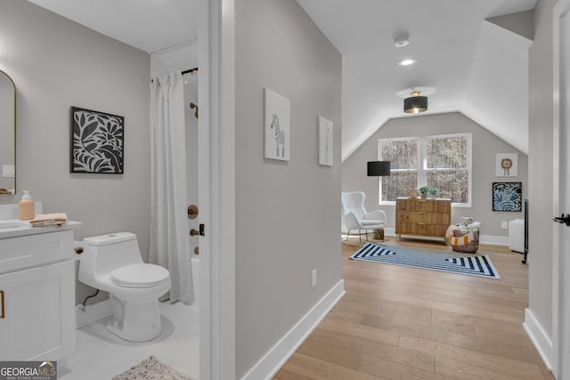 bathroom with lofted ceiling, hardwood / wood-style flooring, a shower with shower curtain, vanity, and toilet