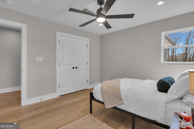 bedroom featuring ceiling fan, light hardwood / wood-style floors, and a closet