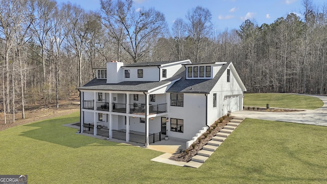 rear view of property featuring a balcony, a garage, and a lawn