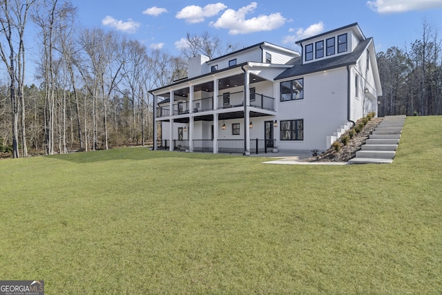 rear view of house with a balcony and a yard