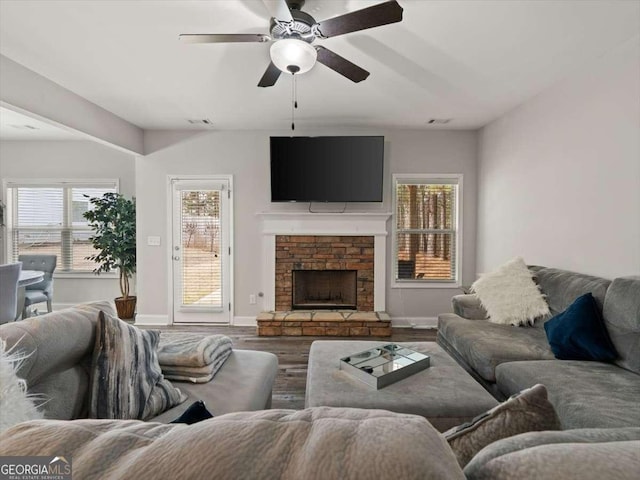 living room featuring ceiling fan, hardwood / wood-style flooring, a fireplace, and a healthy amount of sunlight