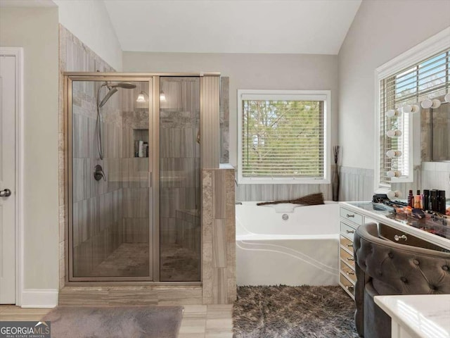 bathroom featuring lofted ceiling, independent shower and bath, and vanity